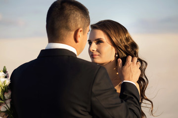 Unusual wedding photo shoot in the desert, the groom straightens the hair of the bride