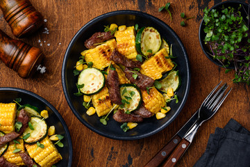 Beef salad with corn, zucchini and micro greens on a wooden table. Healthy food. Top view