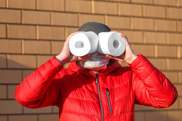 A man in a medical mask holds rolls of toilet paper