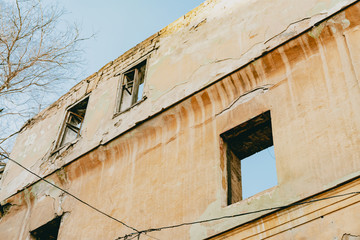Fototapeta na wymiar Old abandoned broken historical building. House without windows and roof. Ruined facade. Destroyed history. Urban. Architecture. City. Bad condition. Real estate. Renovation. Cracked wall