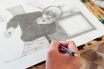 Artist's hand drawing an unfocused pencil illustration. Creative environment 