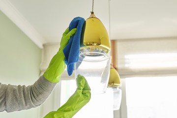 House cleaning, close-up of hands cleaning and polishing lamp