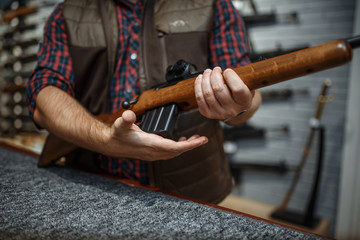 Man loads a rifle at counter in gun shop