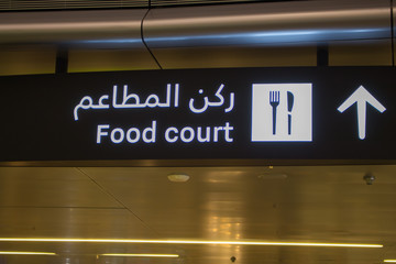 Doha, Qatar - 02/16/2020: Sign with text "food court" in English and Arabian in airport in Doha. Interior of international airport in Doha, Qatar. Food court logo with arrow. 