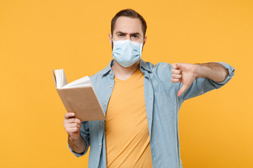 Dissatisfied young man in sterile face mask posing isolated on yellow background in studio....