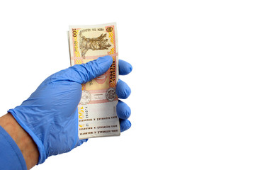 A hand in a medical glove holds the money of the state of the Republic of Moldova, lei, on a white...