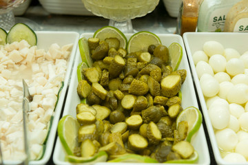 Close-up of pickled cucumber chopped into pieces in a white ceramic bowl.