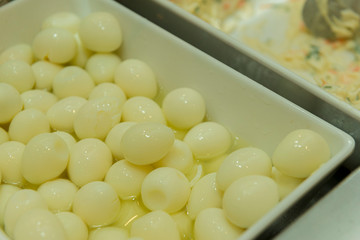 Closeup of quail eggs cooked in white ceramic bowl.