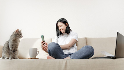The concept of working from home - a young woman was distracted to take a picture of her gray cat...