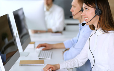 Call center. Group of diverse operators at work. Focus on beautiful asian woman in headset at customer service office. Business concept