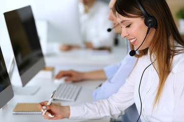 Call center. Group of diverse operators at work. Focus on beautiful asian woman in headset at...