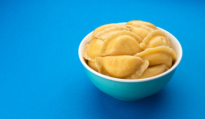 Filled dumplings, russian vareniki, pelmeni on blue background