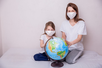 The concept of coronavirus quarantine. Young woman and her daughter in medical masks in isolation at home. The idea of a global virus. Theme of health and medicine. Free space for text
