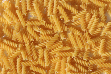 A large quantity of pasta laid flat. the pasta is solid, long, thick, corkscrew or spiral shaped. This shape of pasta is known as Fusilli.