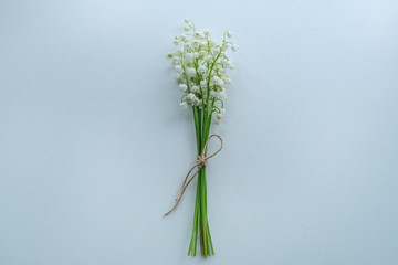 Small bouquet of lilies of the valley with craft rope on white background, top view