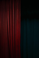 Dark red velvet curtain on one side of a black theatre stage, vertical event background with large...