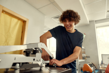 One. Two. Three. Done. Young cheerful male worker using heat press transfer machine for printing...