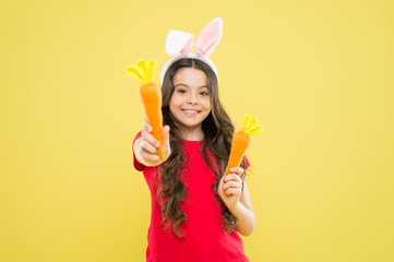 stay healthy and happy. small girl hold carrot. child in bunny ears. nutrition diet for health. benefit of eateing carrot. easter carrot recipes. Making nutritional choice