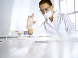 Female laboratory assistant analyzing a blood sample at hospital. Medicine, health care and researching concept