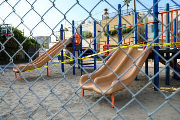 View through chain link fence of closed playground with caution tape