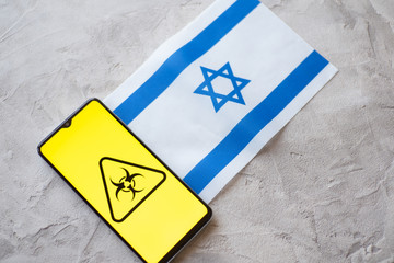 Epidemiological situation in the country Israel. Flag and smartphone with news and a biohazard...