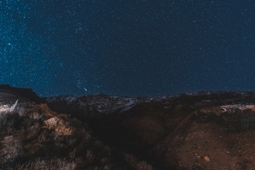 Fototapeta na wymiar Night sky scene with the Milky Way and stars above Morocco in the High Atlas Mountain range between Marrakesh, Ait Ben Haddou and Ouarzazate. Snow capped mountains and dark sky.