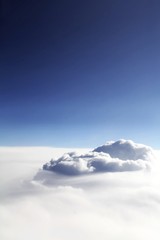 Photo of clouds from an airplane. Above the clouds, a beautiful vertical photo for stories, social networks. Blue sky and white line of clouds. Big white cloud in the center.