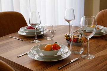 Easter table setting composition with traditional golden painted egg, beautiful tableware on natural dark wood textured table. Top view, copy space, close up, background.