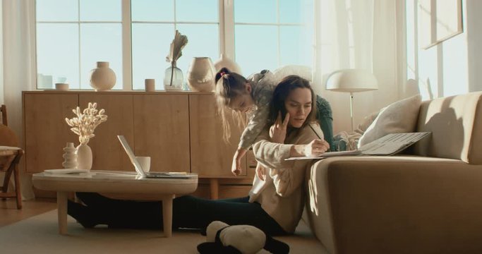 Mother working from home, having a phone call, while her daughter distracts her and drawing attention. Shot on RED Dragon