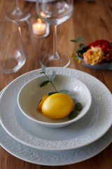 Easter table setting composition with traditional golden painted egg, beautiful tableware on natural dark wood textured table. Top view, copy space, close up, background.