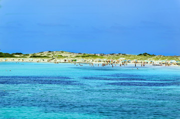 Turquoise sea and people on sandy beach at Formentera, Spain.