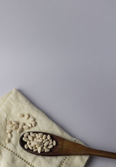 Beans on a cloth napkin and wooden spoon. White background. Top view