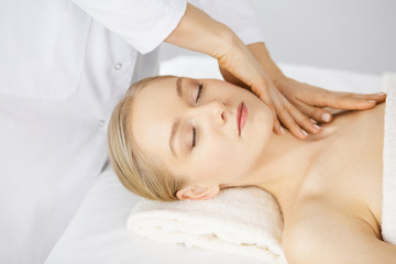 Beautiful caucasian woman enjoying facial massage with closed eyes in spa salon. Relaxing treatment in medicine and Beauty concept