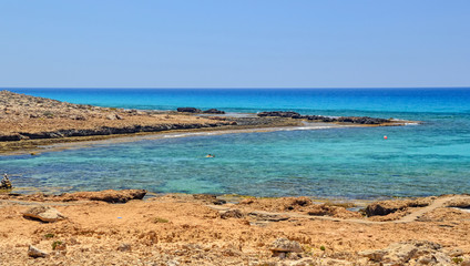 Fototapeta na wymiar Cyprus island, beautiful beach lagoon near Ayia Napa. Turquoise sea water in one of the secluded beaches in Ayia Napa. Secluded and calm wild beach in Mediterranean sea, on Cyprus island.