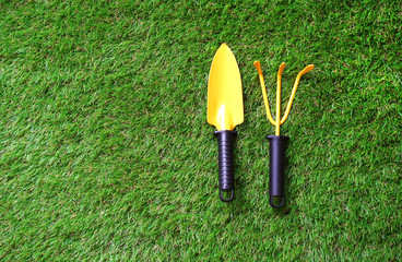 Small garden shovel  and garden rake on artificial grass lawn.