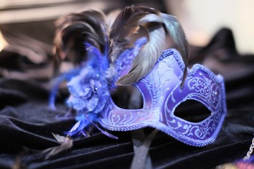 Blue mask for carnival in Venice with feathers and flower against the background of black velvet