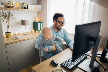 Young father working from home and babysitting his baby boy in the same time.