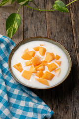 Cantaloupe melon with yogurt in bowl on wooden background