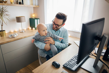 Young father working from home and babysitting his baby boy in the same time.