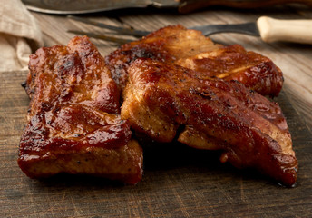 fried juicy pork meat on the bone on a wooden board, grilled meat