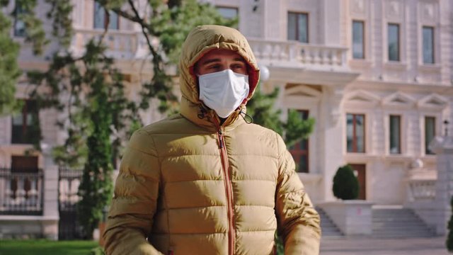 A guy closing his jacket in front of the camera he stand in the middle of the empty street with a protective mask he looking to the sun new Coronavirus mers. Shot on ARRI Alexa Mini