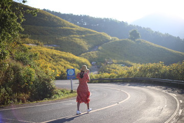 Women are strolling and Mountain scenery filled with yellow flowers or Mexican sunflower (Tung Bua Tong) at Doi Mae U Kho, Mae Hong Son, Thailand.