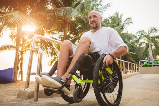 Disabled man in a wheelchair moves on a ramp to the beach.