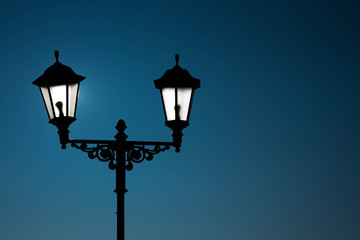 Fototapeta na wymiar Street lamp with lamps in a classic style against a dark blue sky. Dark evening or night.