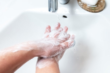 Washing hands with soap under the faucet with water