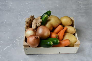 Delivery fresh organic vegetables home. product delivery service. Eco potatoes, carrots, zucchini, onions and ginger in a wooden box. takeaway food in the covid-19 quarantine