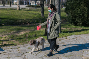 Naklejka na ściany i meble walking dog in the park with face mask