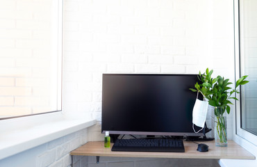 Working from home concept. Quarantine isolation because of coronavirus. Laptop computer, keyboard on wooden table. Face protective mask, disinfectant or sanitizer, cup of tea or coffee. Copy space.