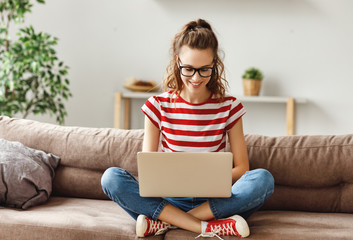 Joyful relaxed woman using laptop with interest at home