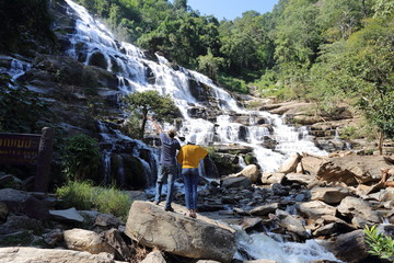 Women and men enjoy the view in Mae Ya waterfall at Doi Inthanon national park, Chiang Mai, Thailand